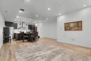 Kitchen featuring light countertops, a breakfast bar area, a center island with sink, dark wood finish cabinetry, and decorative light fixtures