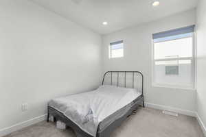 Bedroom with light colored carpet and recessed lighting