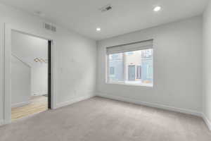 Unfurnished bedroom with light colored carpet and recessed lighting