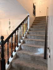 Stairway with wood finished floors and a textured ceiling