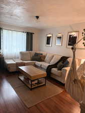 Living room with a textured ceiling and wood finished floors
