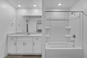 Full bathroom with vanity, bathing tub / shower combination, dark wood-type flooring, and a textured ceiling