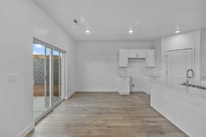 Kitchen with white cabinetry, light wood-type flooring, light stone counters, and recessed lighting