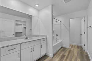 Bathroom with vanity, bathtub / shower combination, and dark wood-style flooring