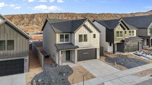 Modern farmhouse with stone siding, board and batten siding, a garage, concrete driveway, and a mountain view