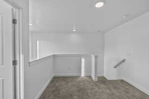 Stairs with carpet floors and recessed lighting