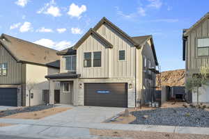 Modern farmhouse featuring an attached garage, board and batten siding, concrete driveway, and stone siding