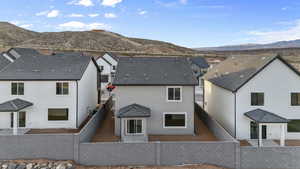 Rear view of house featuring a fenced backyard, a mountain view, and stucco siding