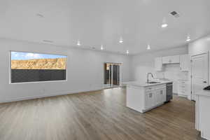 Kitchen with white cabinetry, dark wood-style floors, an island with sink, open floor plan, and light stone counters
