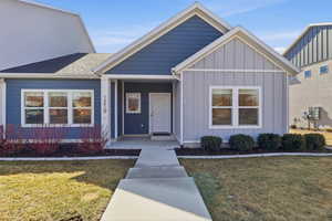 View of front of house with board and batten siding, a front yard, and a porch