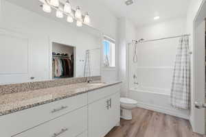 Bathroom with vanity, a spacious closet, light wood finished floors, and shower / bath combo with shower curtain