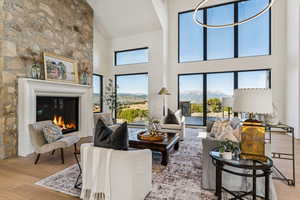 Living room featuring wood finished floors, a towering ceiling, plenty of natural light, a glass covered fireplace, and a mountain view