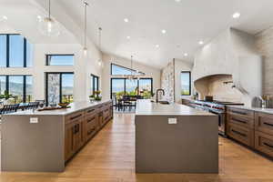 Kitchen featuring light stone counters, decorative light fixtures, recessed lighting, range with two ovens, and light wood-style flooring