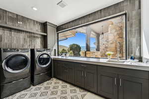 Laundry room with washer and dryer, cabinet space, recessed lighting, tile walls, and light flooring