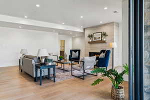Living room with recessed lighting, light wood-type flooring, and a fireplace