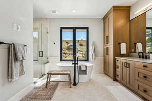 Bathroom with vanity, a stall shower, a soaking tub, tile walls, and a wainscoted wall