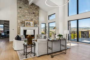 Living area featuring high vaulted ceiling, a mountain view, hardwood / wood-style flooring, beam ceiling, and a lit fireplace