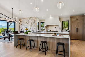 Kitchen with brown cabinetry, hanging light fixtures, plenty of natural light, light wood-type flooring, and recessed lighting