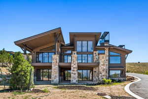 Rear view of house featuring stone siding and a patio