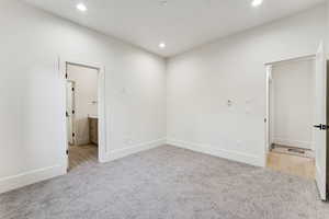 Unfurnished bedroom featuring recessed lighting, light colored carpet, and connected bathroom