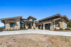 View of front of home with stone siding, driveway, and a garage