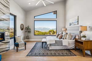 Bedroom with light wood-style flooring, a glass covered fireplace, a mountain view, ceiling fan, and recessed lighting