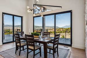 Dining space with a mountain view, light wood-type flooring, a chandelier, and a towering ceiling
