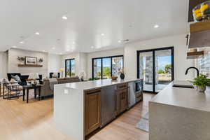 Kitchen with light stone countertops, recessed lighting, light wood finished floors, open floor plan, and black microwave