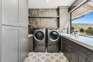 Laundry room with cabinet space, tile walls, and washing machine and clothes dryer