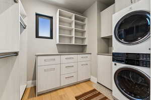 Laundry room with estacked washer and dryer, light wood finished floors, and cabinet space