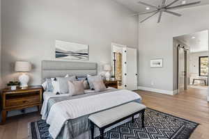 Bedroom with hardwood / wood-style floors, a high ceiling, a ceiling fan, recessed lighting, and a barn door