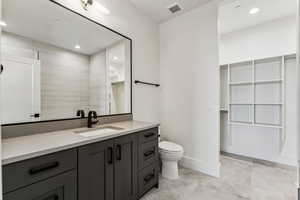 Full bath with recessed lighting, vanity, and a spacious closet