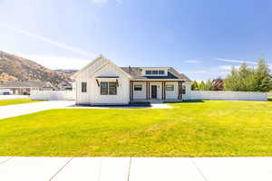 Modern farmhouse featuring board and batten siding, covered porch, a shingled roof, and a mountain view