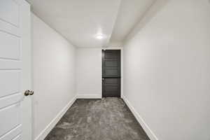 Unfurnished room featuring dark carpet and baseboards