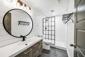Bathroom featuring vanity, walk in shower, dark tile patterned flooring, recessed lighting, and wooden walls