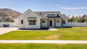 Modern inspired farmhouse with board and batten siding, covered porch, a shingled roof, and driveway