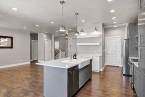 Kitchen with open shelves, a center island with sink, two tone color scheme, stainless steel appliances, and pendant lighting