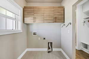 Laundry room featuring electric dryer hookup, washer hookup, cabinet space, and wood tiled floors