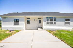 Ranch-style house with a front yard, a shingled roof, and a patio