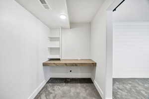 Unfurnished office featuring light carpet, a textured ceiling, and built in desk