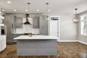 Kitchen featuring gray cabinets, stainless steel appliances, backsplash, dark wood-style floors, and light stone countertops