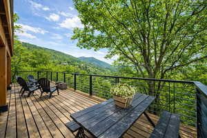 Wooden terrace featuring a view of trees and a fire pit