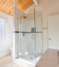 Full bath with a stall shower, a vaulted wooden ceiling, wood walls, and wood finished floors
