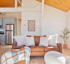 Living area with light wood-style flooring, a vaulted wooden ceiling, and wooden walls