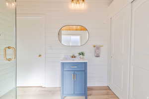 Bathroom featuring vanity, light wood-style flooring, and wooden walls