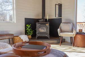 Living area featuring plenty of natural light, wooden walls, and a wood stove