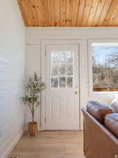 Doorway to outside with wood ceiling, wood finished floors, and wood walls