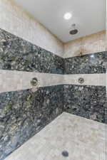 Full bathroom featuring tiled shower and tile walls