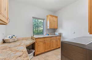 Laundry room with cabinet space, washing machine and clothes dryer, and light stone finish flooring