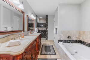 Bathroom featuring double vanity, a tub with jets, and a stall shower